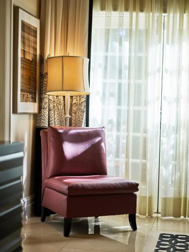 a red chair sitting in front of a window at Hotel Bel-Air - Dorchester Collection in Los Angeles