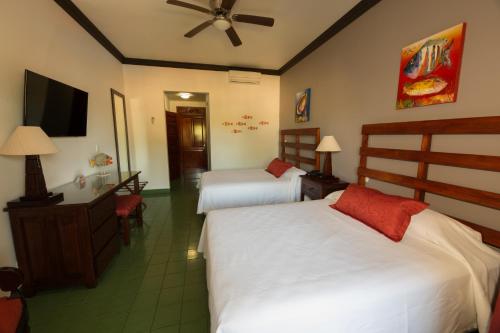 a hotel room with two beds and a flat screen tv at Club del Mar Oceanfront in Jacó