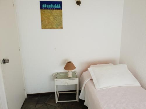 a small bedroom with a bed and a table with a lamp at Vendaval 301 in Punta del Este