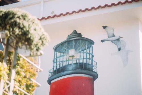 a bird cage on top of a red lighthouse at The Lighthouse in Trappeto