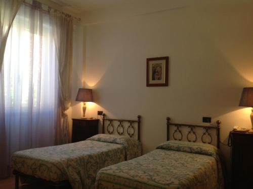 a hotel room with two beds and a window at Ospitalità San Tommaso d'Aquino in Bologna