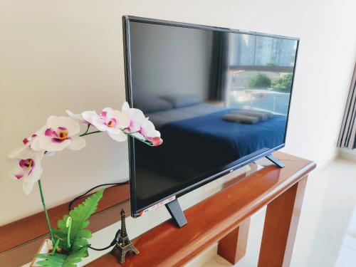 TV de pantalla plana sentada en una mesa con flores en Sky S House, en São Paulo