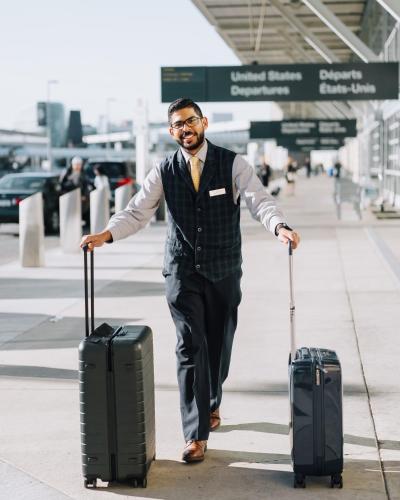 a man walking with two suitcases on the sidewalk at Fairmont Vancouver Airport In-Terminal Hotel in Richmond