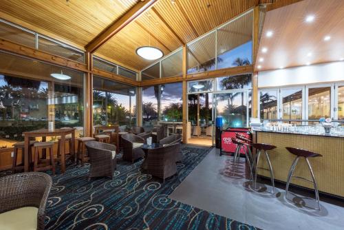 un restaurante con bar, mesas y sillas en Copthorne Hotel & Resort Bay Of Islands, en Paihia