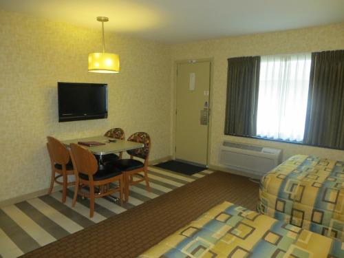 um quarto de hotel com uma mesa e cadeiras e uma televisão em Carleton of Oak Park em Oak Park