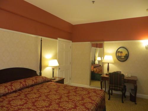 a hotel room with a bed and a desk with a chair at Carleton of Oak Park in Oak Park