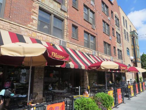 a restaurant with tables and umbrellas in front of a building at Carleton of Oak Park in Oak Park