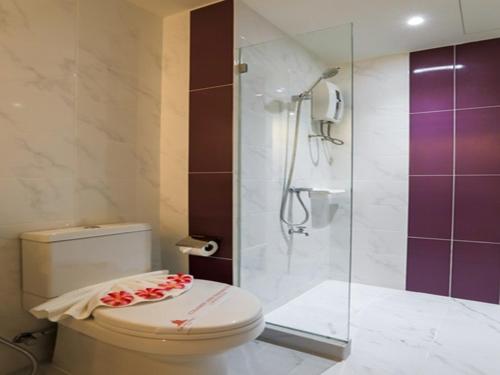 a bathroom with a toilet and a glass shower at Grand Pink Hotel Hatyai in Hat Yai