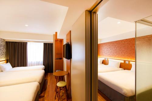 a hotel room with two beds and a stool at karaksa hotel grande Shin-Osaka Tower in Osaka
