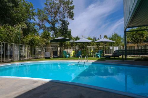 a pool with a lawn chair and a blue umbrella at BIG4 Wangaratta North Cedars Holiday Park in Wangaratta