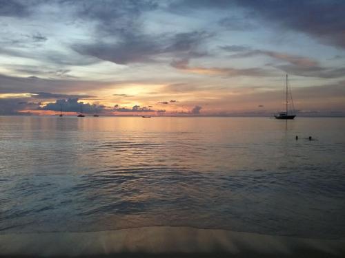a sail boat in the water at sunset at Dewa Phuket Resort & Villas, Nai Yang Beach in Nai Yang Beach