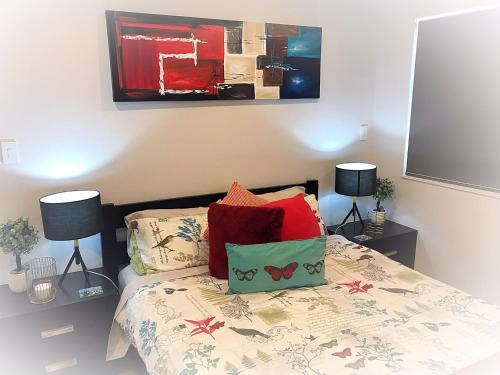 a bedroom with a bed with red pillows at Flat Bush Holiday Accomodation in Auckland