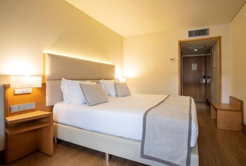 a hotel room with a large white bed and a night stand at The Azoriani Boutique, Ascend Hotel Collection in Ponta Delgada