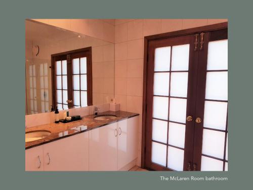 een badkamer met 2 wastafels en een grote spiegel bij Chapel Hill Winery Guest House in McLaren Vale