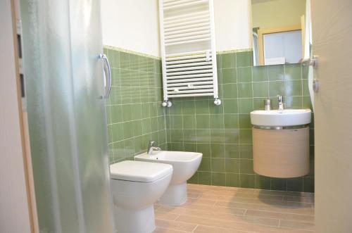 a green tiled bathroom with a toilet and a sink at Affittacamere Rubino Guest House in Ponte nellʼAlpi