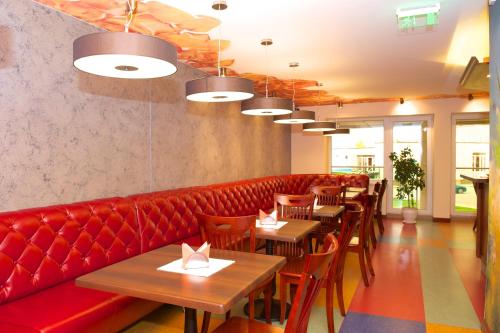 a restaurant with a red couch and tables and chairs at SPA Amber Palace in Šventoji