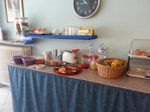a counter with a table with food and a clock at Hotel Lombardia in Seveso