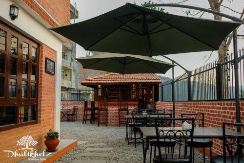 a patio with tables and chairs and an umbrella at Dhulikhel boutique hotel in Dhulikhel