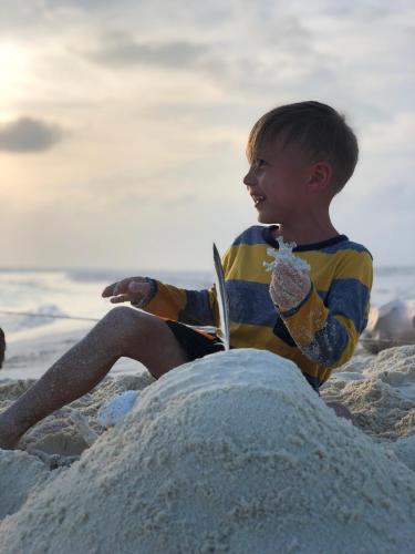 a young boy sitting on the beach reading a book at Mariana Maldives in Gaafaru