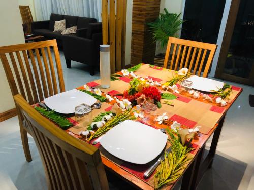 a dining room table with two white plates and flowers on it at Mariana Maldives in Gaafaru