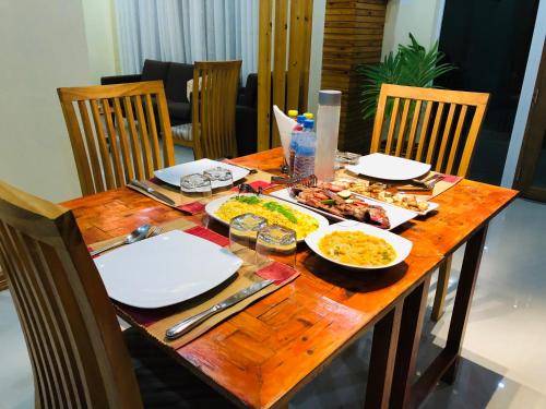 a wooden table with plates of food on it at Mariana Maldives in Gaafaru