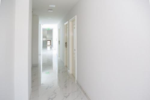 a white hallway with white walls and white marble floors at Rich8 Hostel in Bangkok