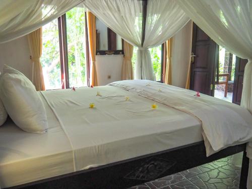 a bed with white sheets and yellow candles on it at Scuba Tribe Bali dive-resort in Tulamben