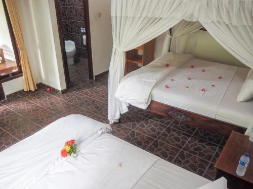 two beds in a hotel room with flowers on them at Scuba Tribe Bali dive-resort in Tulamben