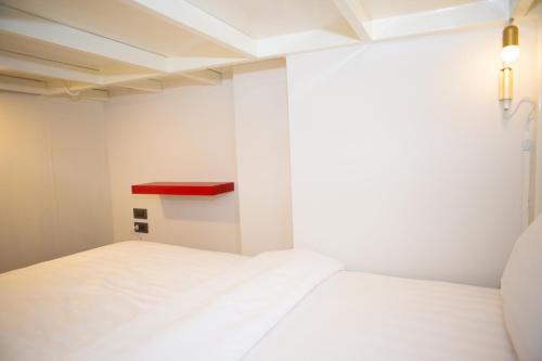 a bedroom with two white beds and a red shelf at Rich8 Hostel in Bangkok