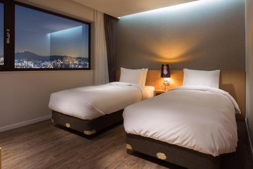 two beds in a hotel room with a window at Amanti Hotel Seoul in Seoul