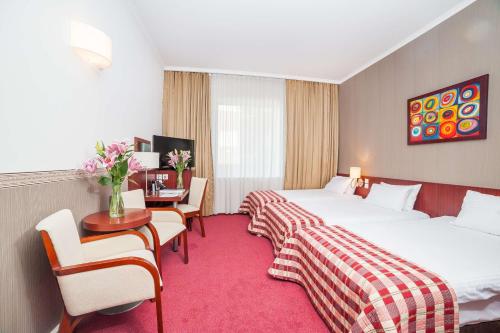 a hotel room with two beds and a desk at Premier Kraków Hotel in Kraków
