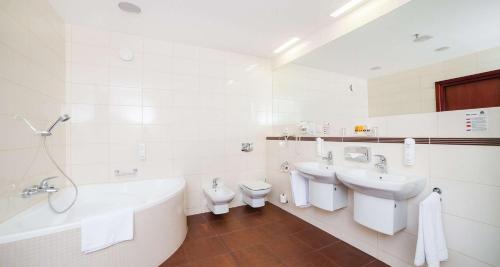 a white bathroom with two sinks and a toilet at Premier Kraków Hotel in Kraków