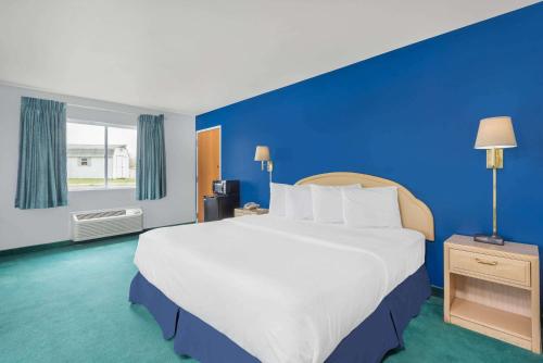 a large bed in a room with a blue wall at Days Inn by Wyndham Osage Beach Lake of the Ozarks in Osage Beach