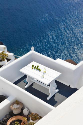 a white table with drinks on top of the ocean at Homeric Poems in Fira