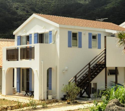 ein weißes Haus mit blauen Fenstern und einer Treppe in der Unterkunft Vacances a la mer Ishigaki in Ishigaki-jima