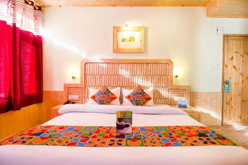 a bedroom with a large bed with a colorful blanket at FabExpress Shami Inn Naggar Road in Manāli