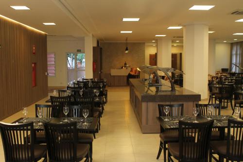a dining room with tables and chairs and a bar at The Hill Hotéis Executive in São Carlos