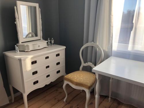 Vestidor blanco con espejo y silla en Skrunda Apartments Elandrum, en Skrunda