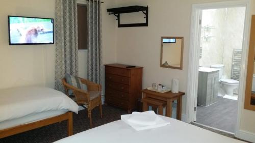 a bedroom with a bed a dresser and a bathroom at Guesthouse At Rempstone in Loughborough