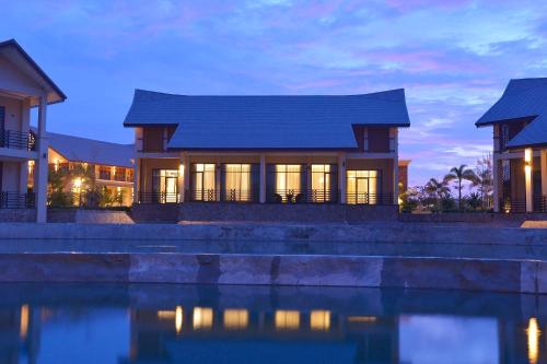 a house with a reflection in the water at night at Emerald Palace Hotel in Nay Pyi Taw