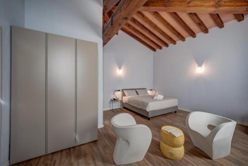 a bedroom with a bed and two white chairs at Hotel Cortaccia Sanvitale in Sala Baganza