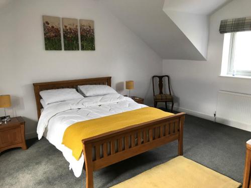 a bedroom with a large bed with a yellow blanket at Pepperpot Cottage in Skipton