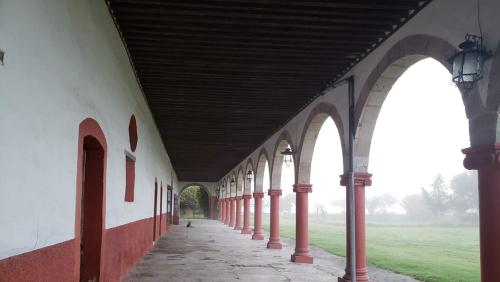 an empty building with red and white walls and arches at Ex-Hacienda San Buenaventura in San Lorenzo Soltepec