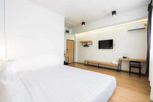 a bedroom with a white bed and a flat screen tv at Marwin Villa in Bangkok
