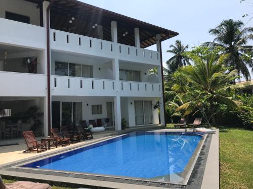 una villa con piscina frente a un edificio en Jippie The Villa, en Hikkaduwa