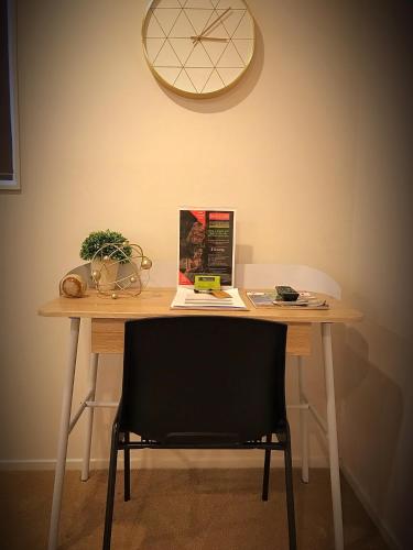 a wooden table with a chair and a clock on the wall at Flat Bush Holiday Accomodation in Auckland