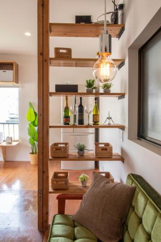 a living room with a green couch and shelves with wine glasses at CRAFT in Matsubara