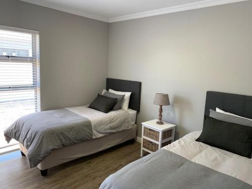 a bedroom with two beds and a lamp and a window at 679 Morsvalla Way Langebaan Golf Estate in Langebaan