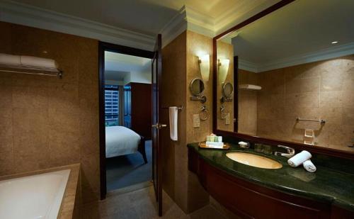 a bathroom with a sink and a mirror and a bed at Better Residence Suite at Times Square KL in Kuala Lumpur