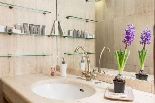 a bathroom with a sink with purple flowers in a vase at Cedro Terrace&Jacuzzi - Loft in Trastevere in Rome